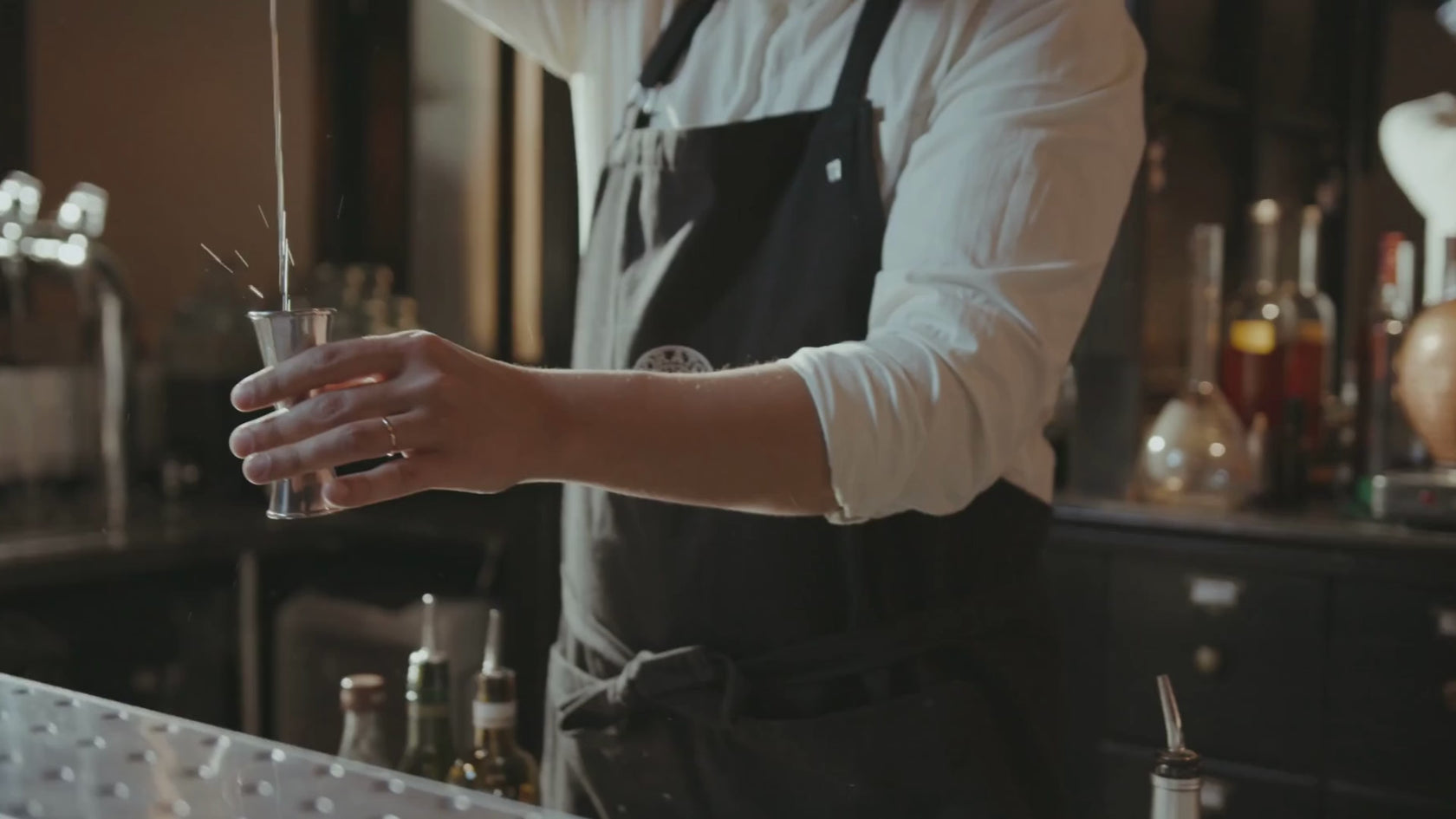 Bartender pouring a shot in a jigger