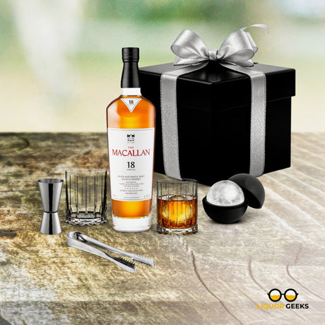 Macallan 18 whiskey bottle with a glass and cocktail tools on a wooden surface.