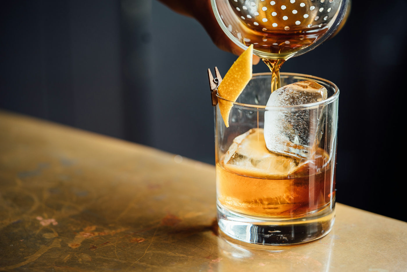 Whiskey being poured over ice at a dark bar — Liquor Geeks taste quiz background